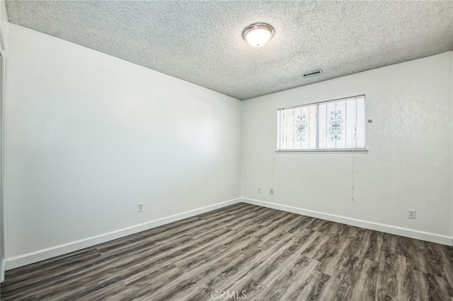 unfurnished room with a textured ceiling and dark hardwood / wood-style floors