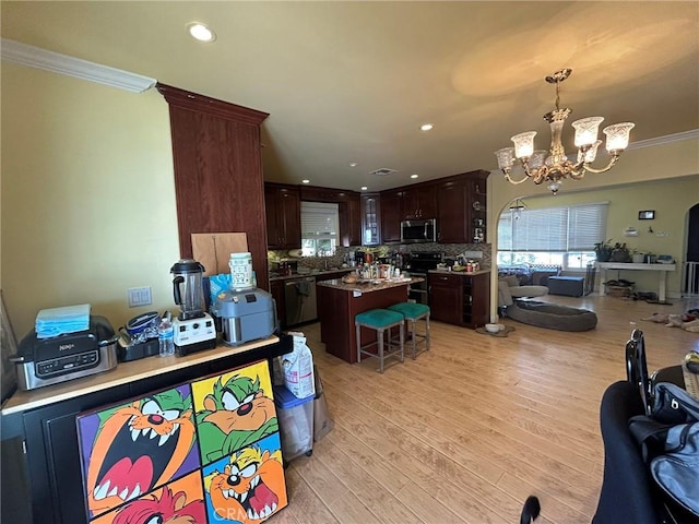 interior space featuring light wood-type flooring, dark brown cabinets, stainless steel appliances, a kitchen island, and hanging light fixtures