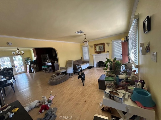 living room featuring an inviting chandelier, light hardwood / wood-style flooring, and crown molding