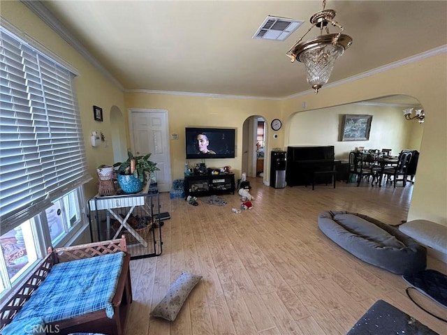 living room with wood-type flooring, ornamental molding, and an inviting chandelier