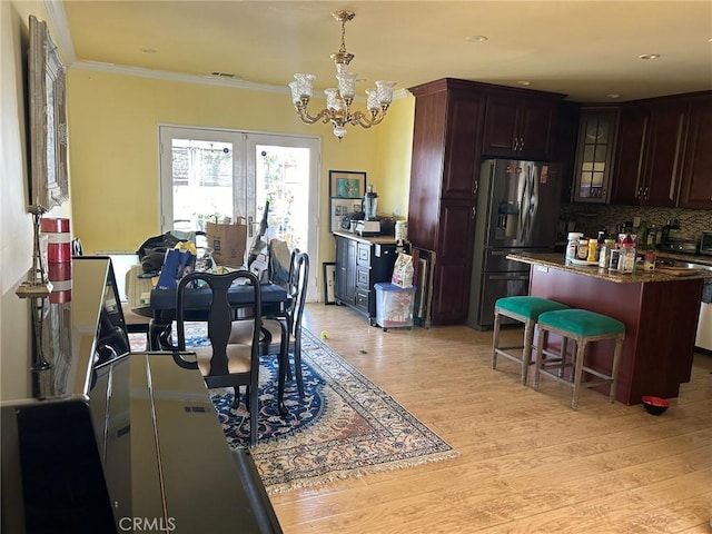 dining room with light wood-type flooring, ornamental molding, and a notable chandelier