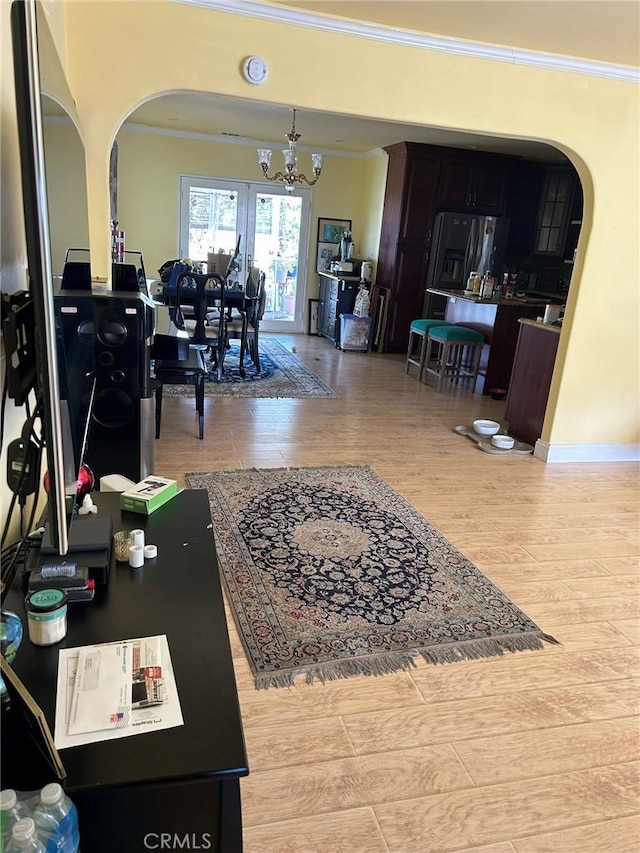 living room with crown molding, light hardwood / wood-style floors, and an inviting chandelier