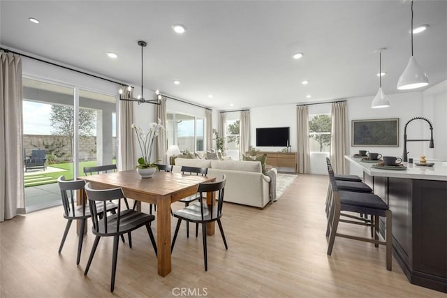 dining space featuring sink, light hardwood / wood-style flooring, and a notable chandelier