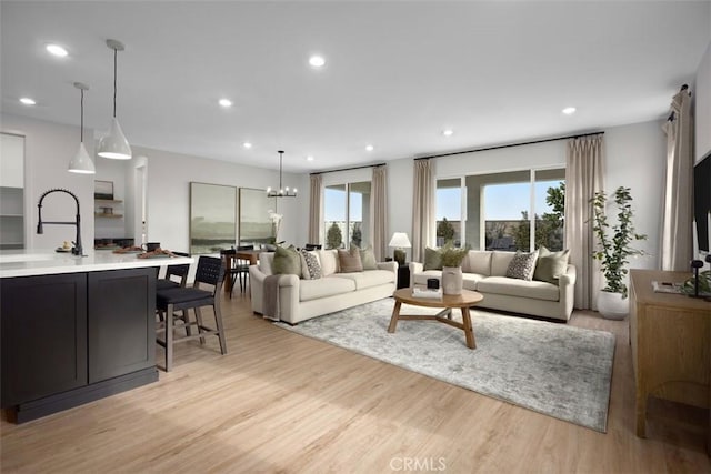 living room featuring a chandelier, light hardwood / wood-style floors, and sink