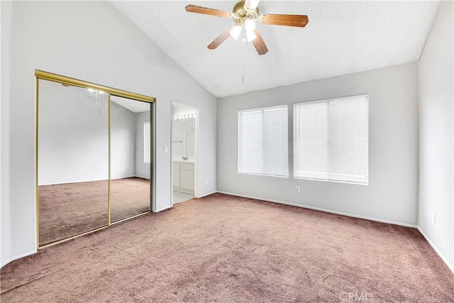 unfurnished bedroom with vaulted ceiling, ceiling fan, carpet flooring, and ensuite bath