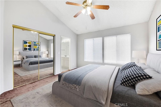 carpeted bedroom featuring ceiling fan, a closet, connected bathroom, and lofted ceiling