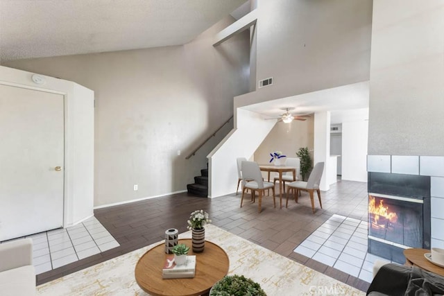 living room featuring ceiling fan, tile patterned flooring, a fireplace, and high vaulted ceiling