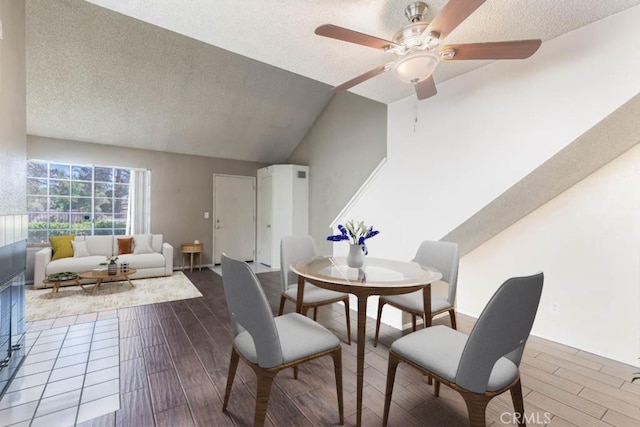 dining space featuring ceiling fan, vaulted ceiling, and a textured ceiling