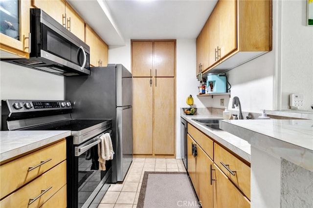 kitchen with light stone countertops, sink, light tile patterned floors, and stainless steel appliances