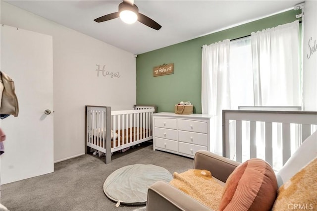 carpeted bedroom with a nursery area and ceiling fan