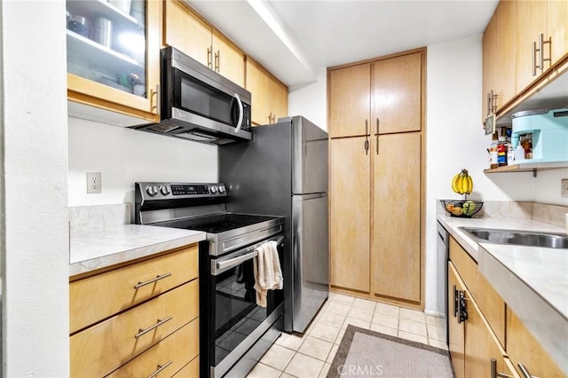 kitchen featuring light tile patterned floors, light brown cabinets, stainless steel appliances, and sink