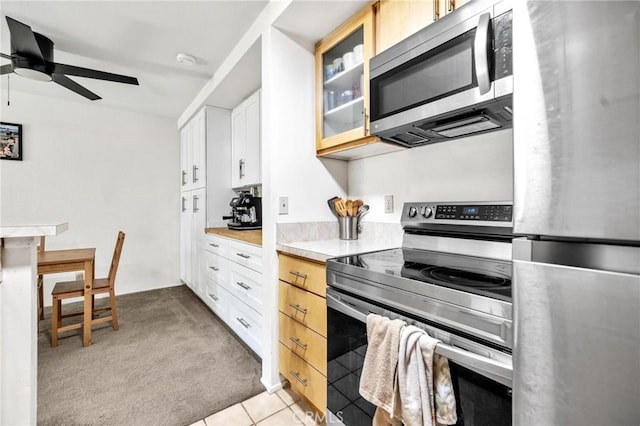 kitchen with white cabinets, light brown cabinetry, stainless steel appliances, and light carpet