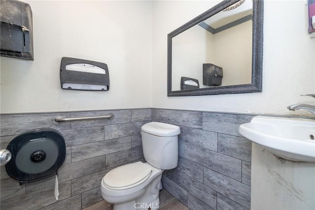 bathroom with wood-type flooring, tile walls, and toilet