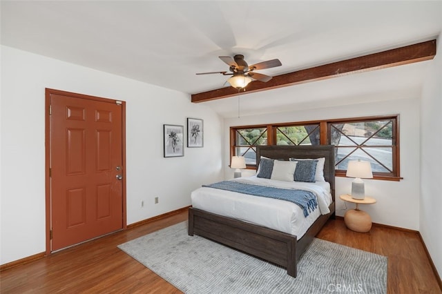 bedroom featuring beamed ceiling, hardwood / wood-style floors, and ceiling fan