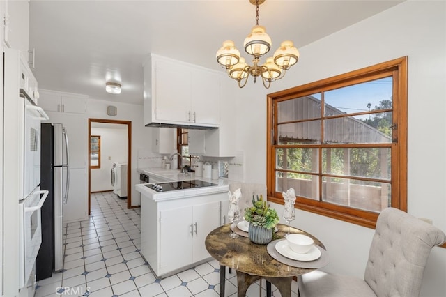 kitchen with washing machine and dryer, white cabinets, pendant lighting, and a notable chandelier