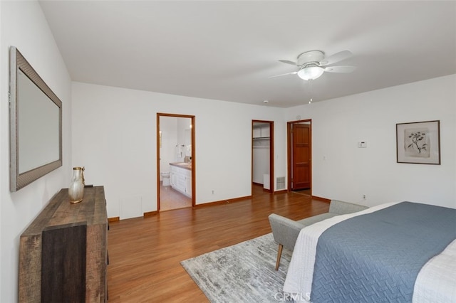 bedroom with connected bathroom, ceiling fan, a spacious closet, a closet, and hardwood / wood-style flooring