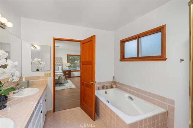 bathroom with plenty of natural light, vanity, a relaxing tiled tub, and tile patterned flooring