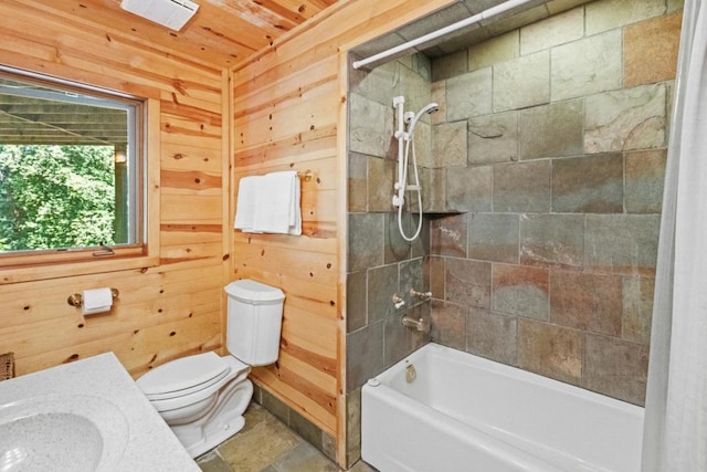 bathroom featuring tiled shower / bath combo, wooden walls, and toilet