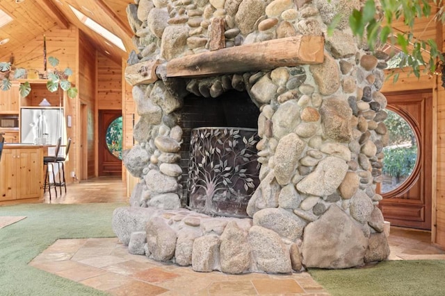 interior details featuring a stone fireplace, carpet, stainless steel refrigerator, and wood walls