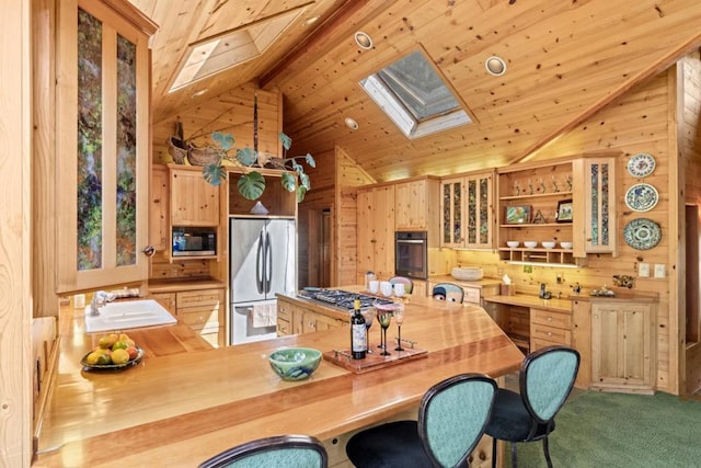 kitchen featuring sink, light brown cabinets, wooden walls, kitchen peninsula, and stainless steel appliances