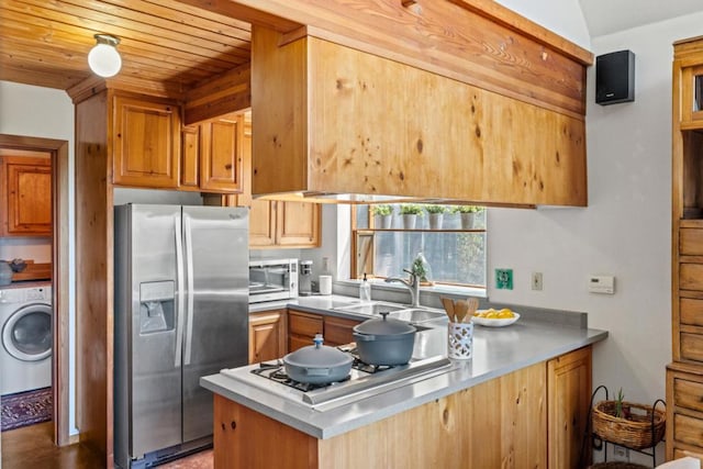 kitchen featuring washer / dryer, sink, kitchen peninsula, stainless steel appliances, and wooden ceiling