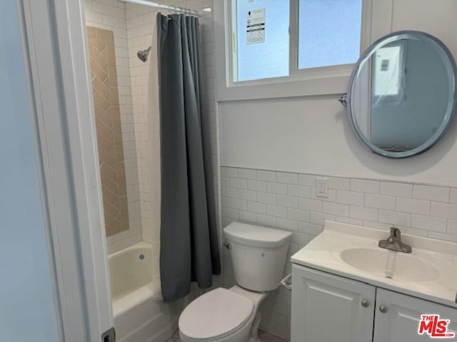 full bathroom with toilet, vanity, shower / tub combo with curtain, and tile walls