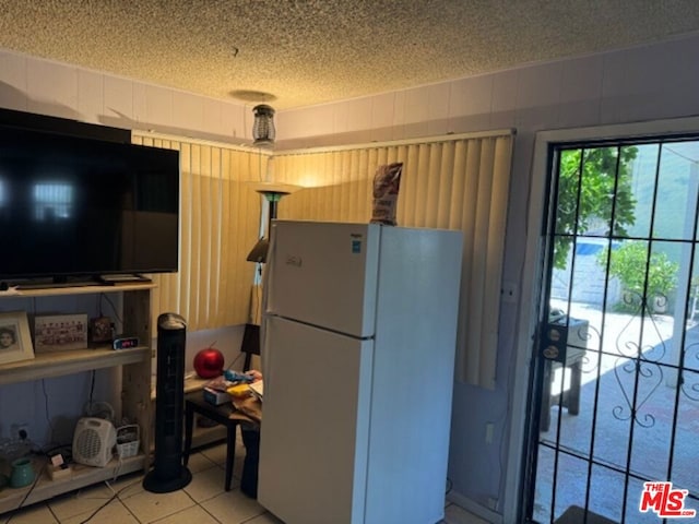 kitchen featuring a textured ceiling, white refrigerator, and tile patterned floors