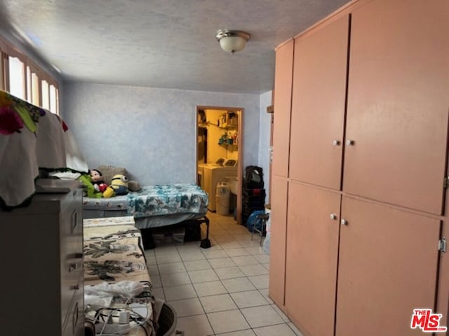 bedroom featuring washer and dryer, light tile patterned floors, and a textured ceiling