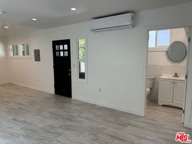 entryway with a wall unit AC, electric panel, and sink