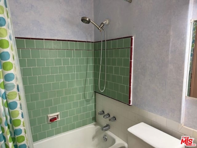 bathroom featuring shower / bathtub combination with curtain and toilet