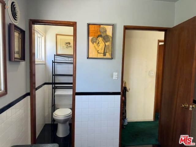 bathroom featuring toilet and tile walls