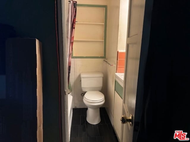 bathroom featuring tile patterned floors, toilet, and tile walls