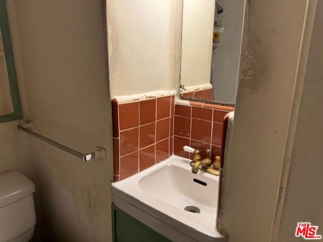 bathroom with vanity, toilet, and backsplash