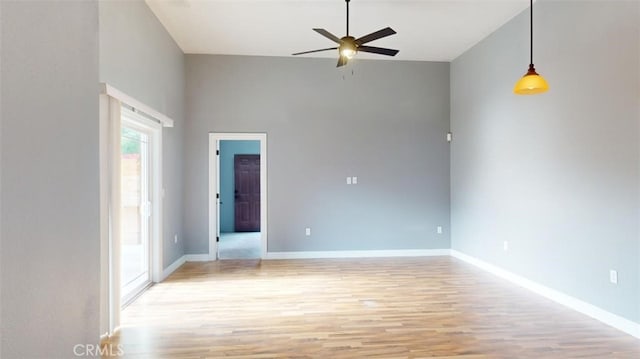 spare room featuring ceiling fan, a high ceiling, and light wood-type flooring