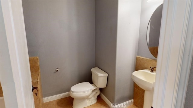 bathroom with toilet, sink, and tile patterned flooring