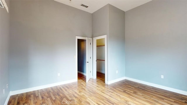 empty room with a high ceiling and light wood-type flooring