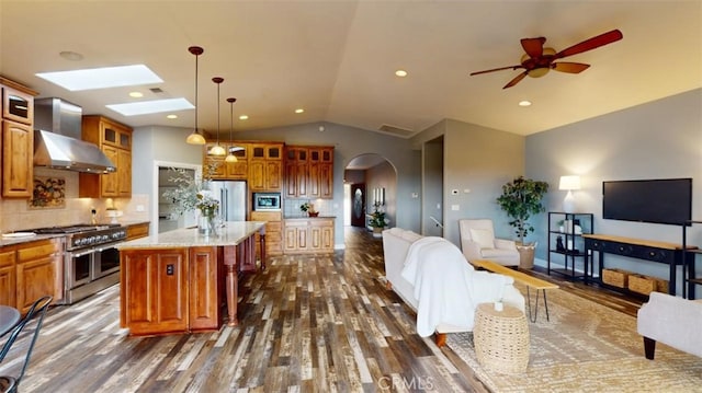 kitchen featuring dark hardwood / wood-style floors, stainless steel appliances, decorative backsplash, and a center island with sink