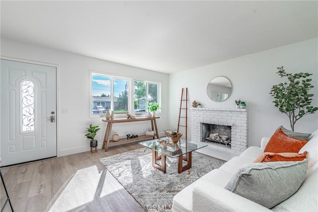 living room with light wood-type flooring and a brick fireplace