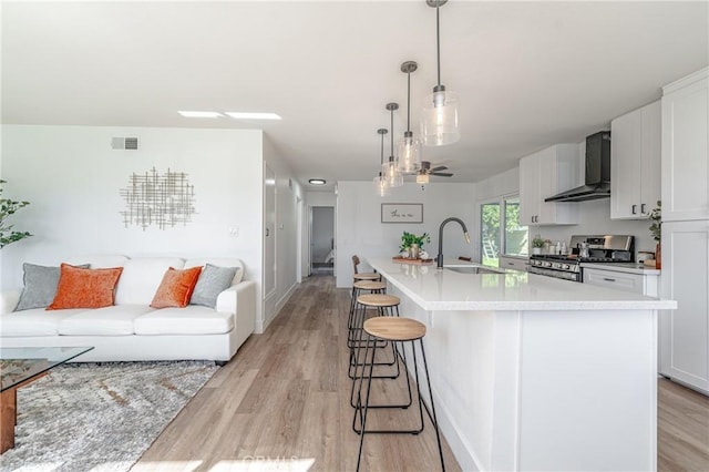 kitchen with white cabinets, sink, wall chimney exhaust hood, and stainless steel gas range