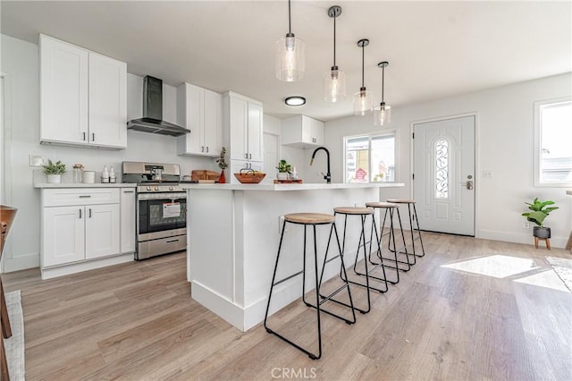 kitchen featuring white cabinets, stainless steel stove, and wall chimney range hood