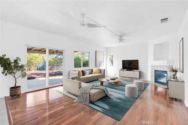 living room with hardwood / wood-style flooring, ceiling fan, and a fireplace