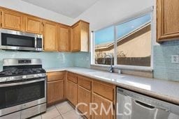 kitchen with backsplash, light tile patterned floors, sink, and appliances with stainless steel finishes