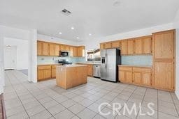 kitchen with a kitchen island, light tile patterned floors, and appliances with stainless steel finishes