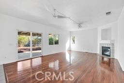 unfurnished living room with ceiling fan, wood-type flooring, and a fireplace