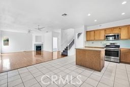 kitchen featuring appliances with stainless steel finishes, light tile patterned floors, a kitchen island, and ceiling fan