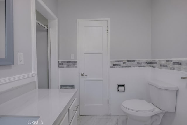 bathroom with vanity, toilet, and tile walls