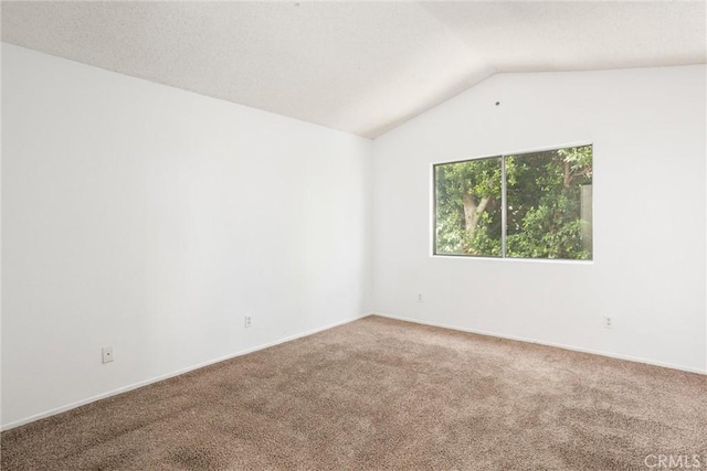 carpeted empty room with vaulted ceiling