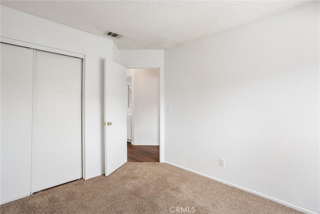 unfurnished bedroom featuring a closet, carpet floors, and a textured ceiling