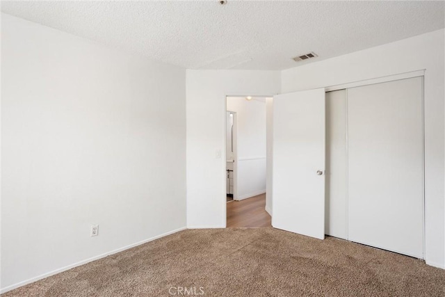 unfurnished bedroom with a closet, carpet floors, and a textured ceiling