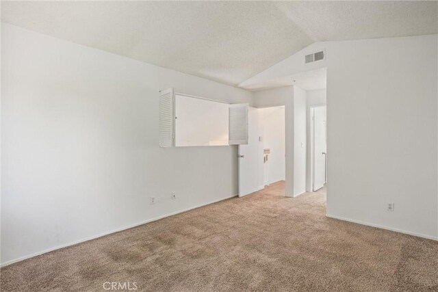 spare room with light carpet and vaulted ceiling